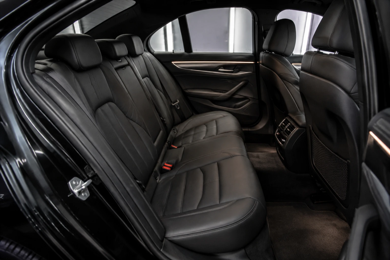 Brand-neutral rear cabin with clean black leather, carpet and door panels