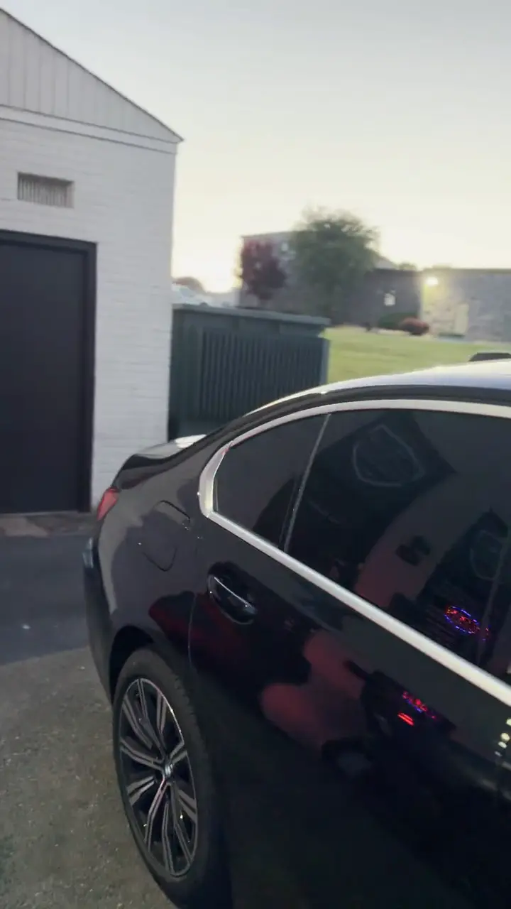 Black sedan at dusk with tinted windows, filmed in a slow walk-around.