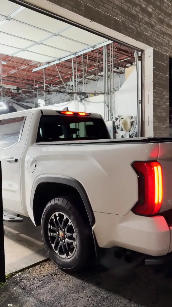 White pickup truck at night with tinted windows, filmed in a slow walk-around.