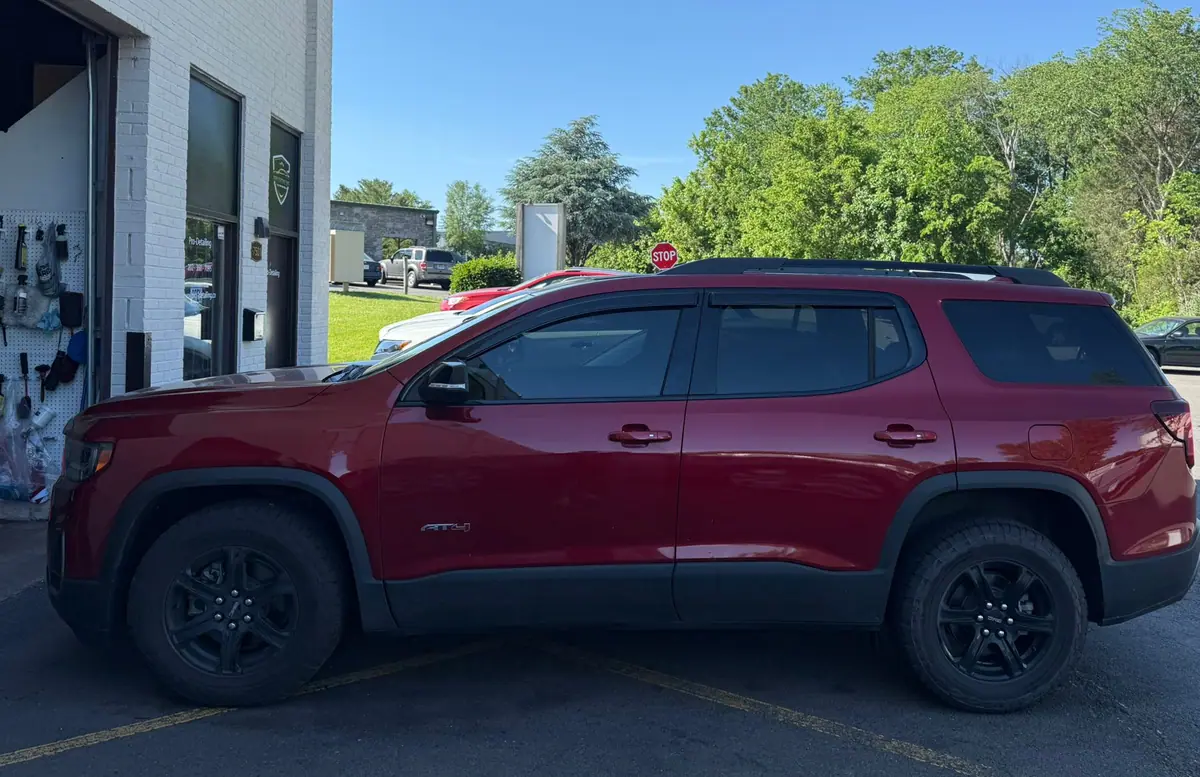 A dark red GMC Acadia AT4 parked in side profile outside the open workshop bay on a clear afternoon. PRO Detailing’s Manassas studio, serving Woodbridge, VA drivers.