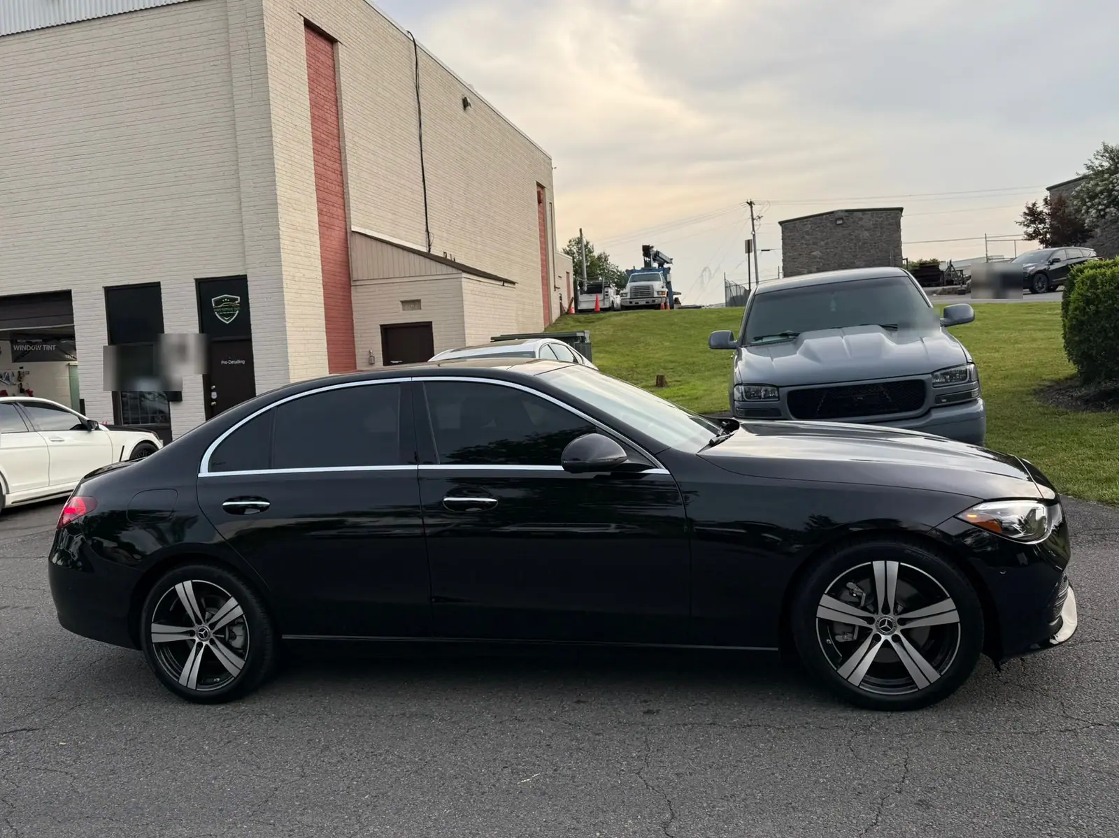 A black Mercedes-Benz saloon parked in profile on the forecourt outside the PRO Detailing unit, roller door open behind it. PRO Detailing’s Manassas studio, serving Gainesville, VA drivers.
